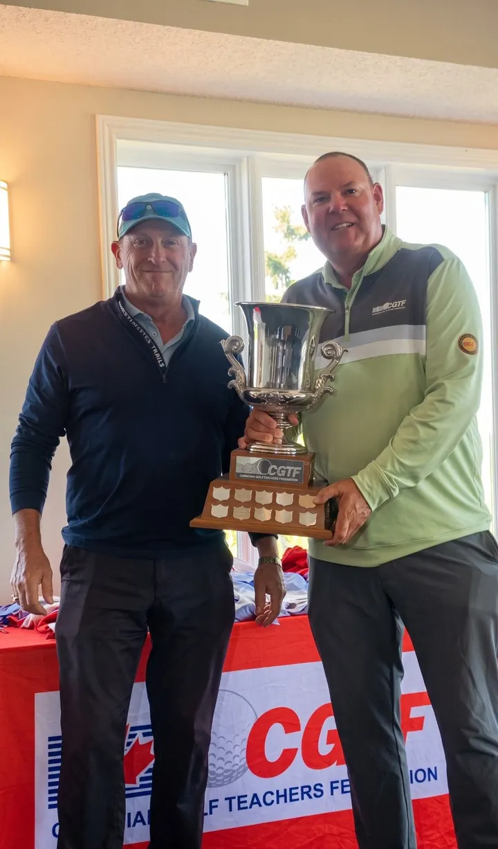 Hai huấn luyện viên cầm cúp CGTF trước bảng hiệu Canadian Golf Teachers Federation